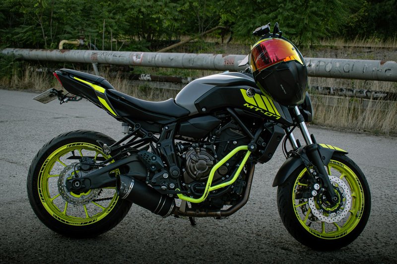 Vibrant black and yellow motorcycle parked outdoors with industrial background.