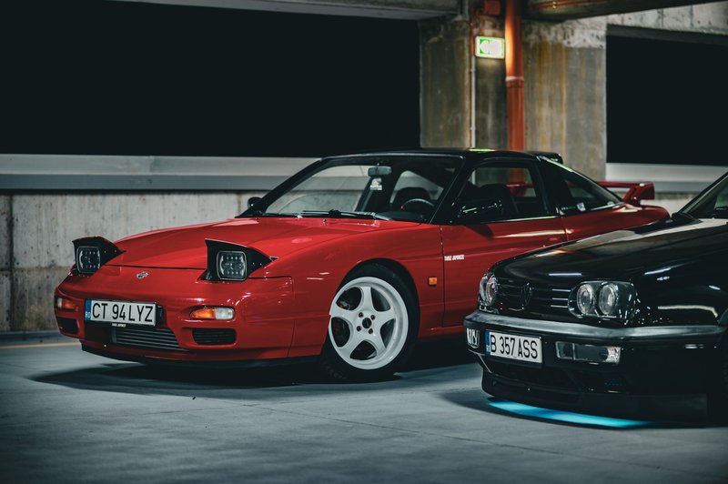 A red sports car with pop-up headlights parked in an urban garage, showcasing a sleek design.