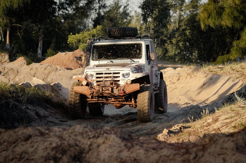 Dynamic off-road driving adventure with a muddy white truck navigating through a desert terrain.