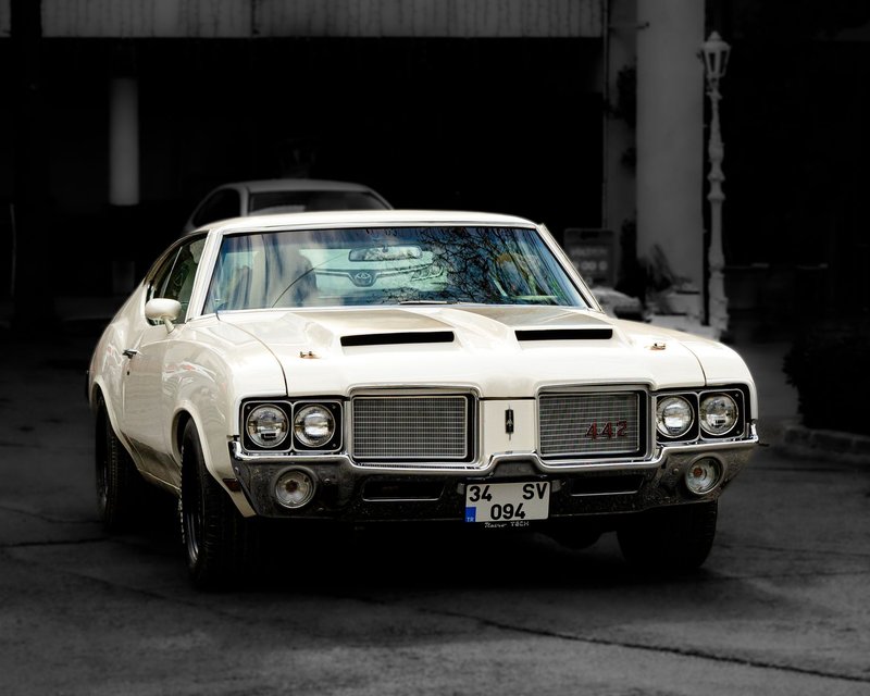Front view of a classic Oldsmobile 442 muscle car in an urban setting.