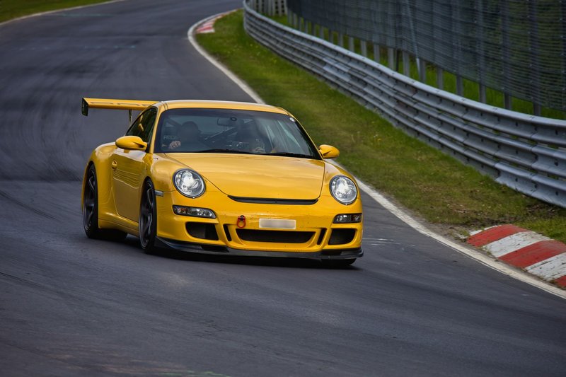 Yellow sports car speeding on a race track, showcasing dynamic performance and design.