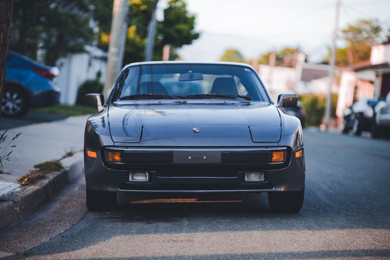 Front view of a classic black sports car parked on a quiet city street.