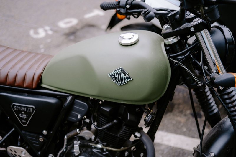 Close-up view of a vintage motorcycle showcasing its olive green gas tank and handlebars.