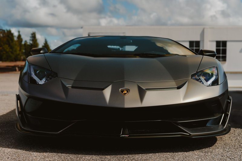 Front view of a stylish black luxury sports car parked outdoors under a clear sky.