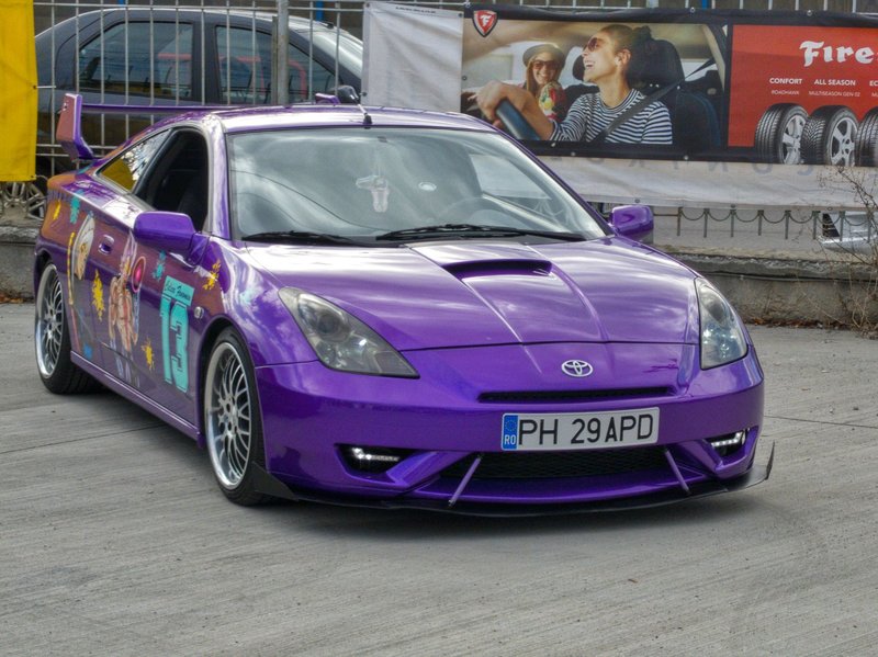Eye-catching purple Toyota Celica with unique designs at an outdoor event.