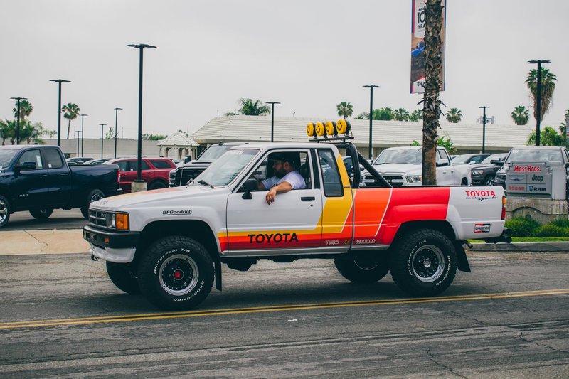 A classic Toyota pickup truck with retro decals at an outdoor car meet. Vibrant colors and iconic design.