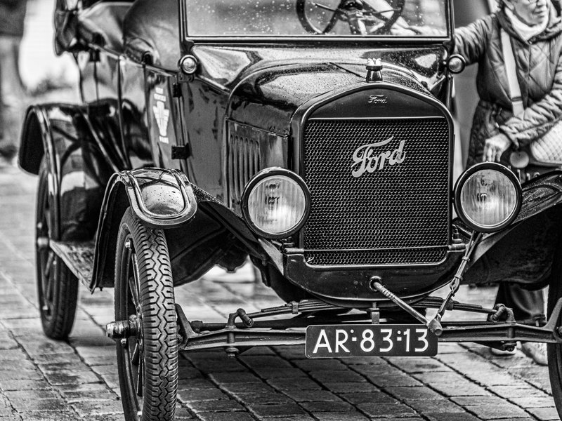 Classic Ford Model T car displayed on cobbled street, black and white photo.