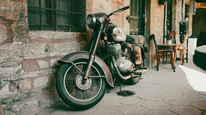 Retro motorcycle parked on a cobblestone sidewalk in an urban alleyway, exuding vintage charm.