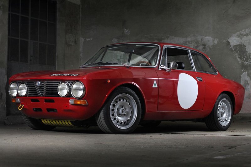 A stunning vintage red classic car parked indoors against an industrial backdrop, showcasing elegance and design.