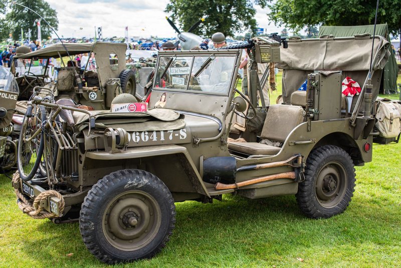 Classic army jeep displayed at a vibrant vehicle festival in the UK.