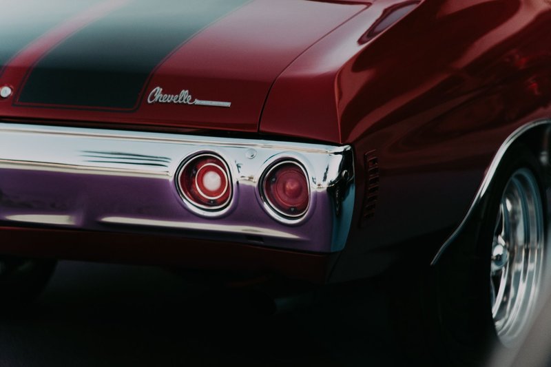 Detailed shot of a vintage red Chevrolet muscle car's rear with chrome detailing.