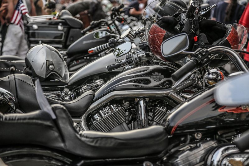 Close-up of stylish parked motorcycles in line, featuring helmets and chrome details at an outdoor event.