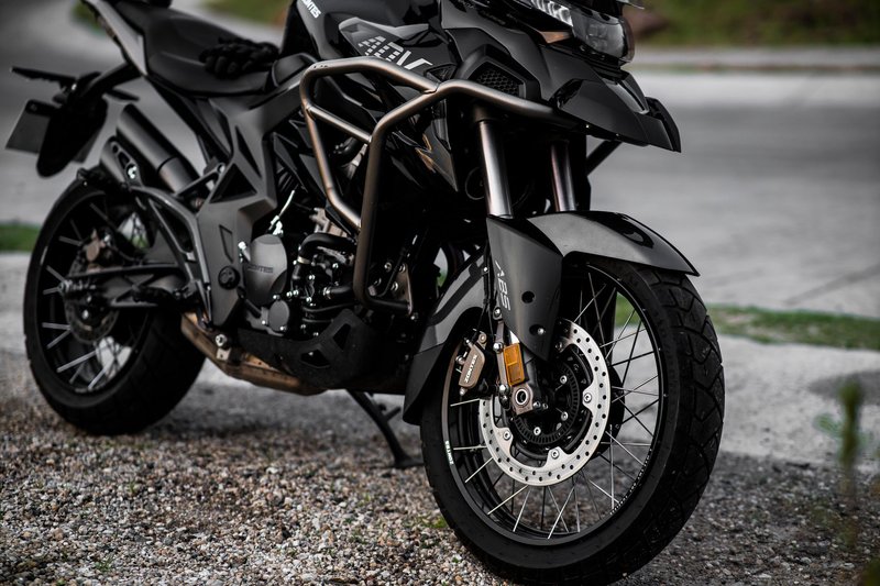 Detailed view of a black motorcycle parked on a gravel road.