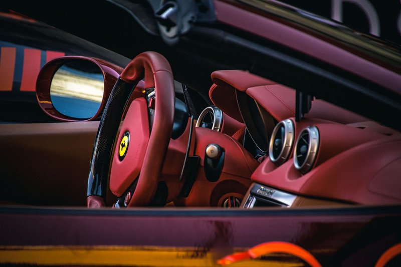 Close-up of a luxury sports car interior showcasing red leather seats and steering.