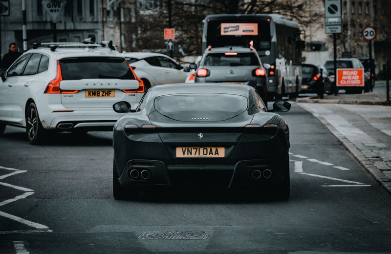 Ferrari Roma amidst busy city traffic in Bath, England, showcasing luxury automotive design.