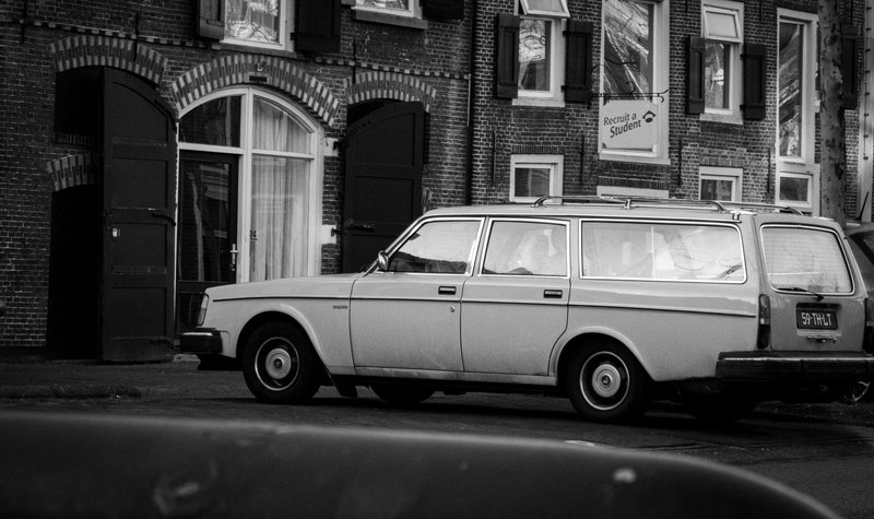 Classic Volvo station wagon parked in an urban setting with historic brick buildings.