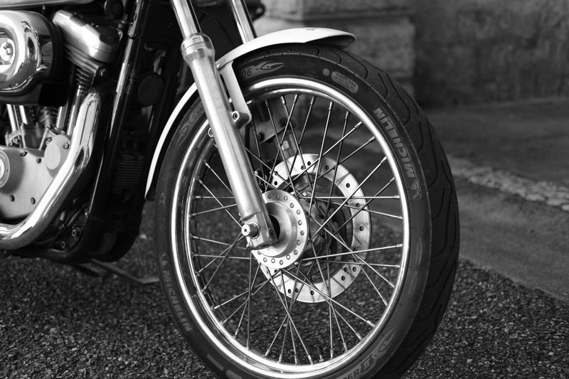Black and white image of a motorcycle wheel showcasing intricate details of the tire and spokes.