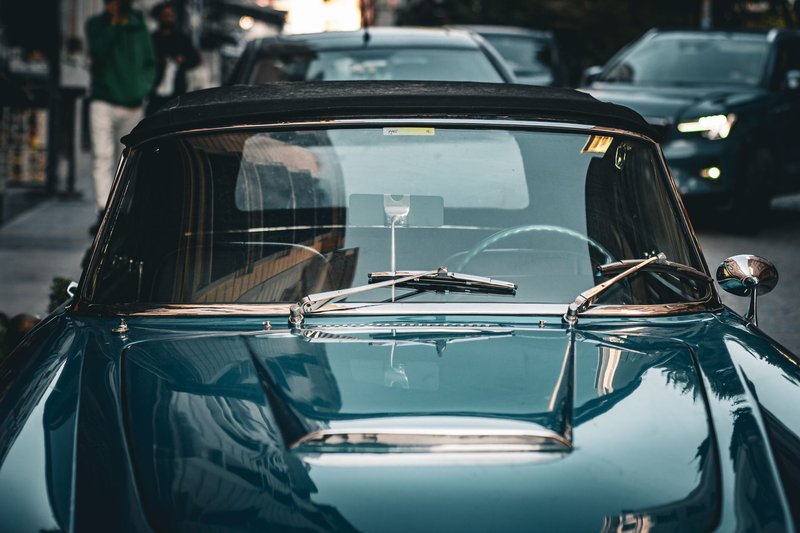A stylish blue vintage convertible parked on a busy urban street depicting retro elegance.
