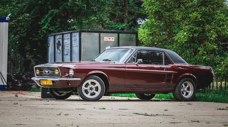 A classic vintage car with brown paint and chrome details parked outdoors on a sunny day.