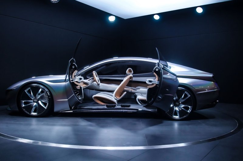 Sleek and modern concept car displayed indoors with open scissor doors, highlighting its futuristic design.