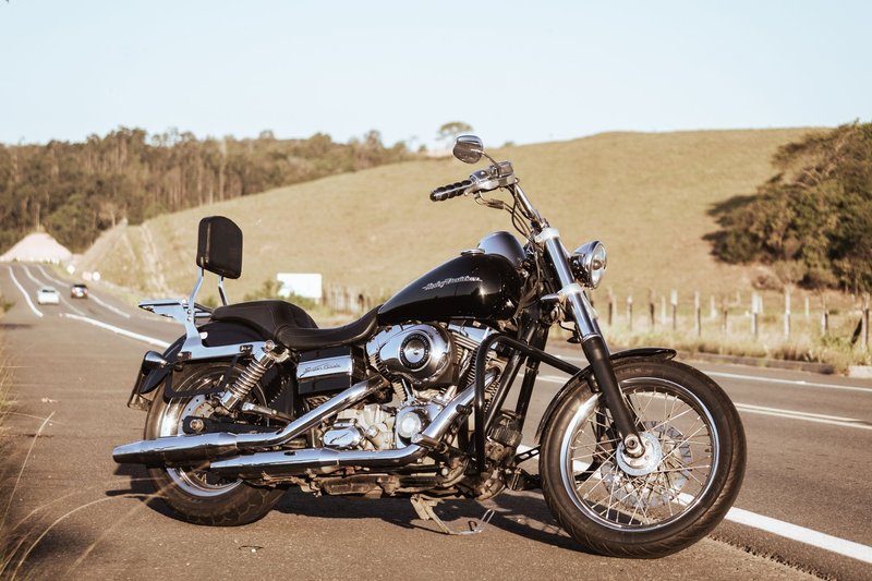 Vintage black motorcycle parked on a scenic open road during a sunny day.