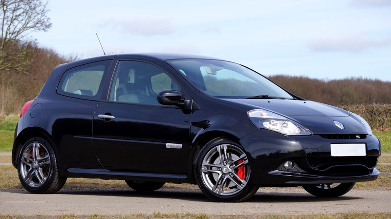 A sleek black Renault Clio RS hatchback parked in a scenic outdoor location.