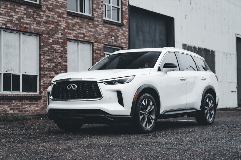 White luxury SUV parked outdoors in front of a brick building, showcasing modern automotive design.