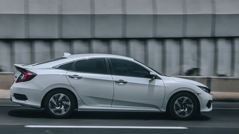 A sleek white car speeding down an urban road, illustrating motion and style.