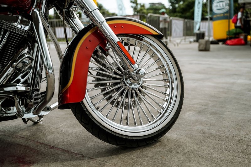 Detailed view of a custom chrome motorcycle wheel with vibrant red fender outdoors in Quezon City.