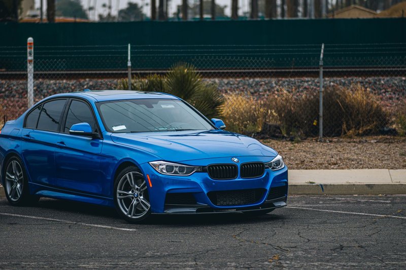 A sleek blue BMW sedan parked on an overcast day, showcasing modern automotive design.