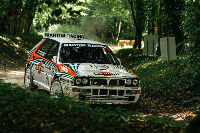 Rally car racing on a forest path in England, showcasing speed and skill.