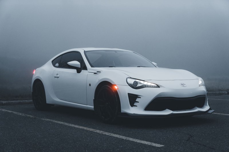 A white Toyota GT86 sports car parked in a foggy outdoor setting.