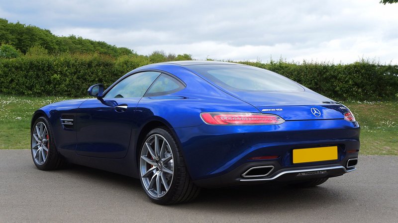 Sleek blue sports car parked outdoors, showcasing elegance in design against a countryside backdrop.