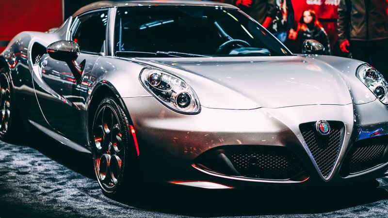 Close-up of a sleek metallic silver sports car at an indoor exhibition showcasing luxury design.