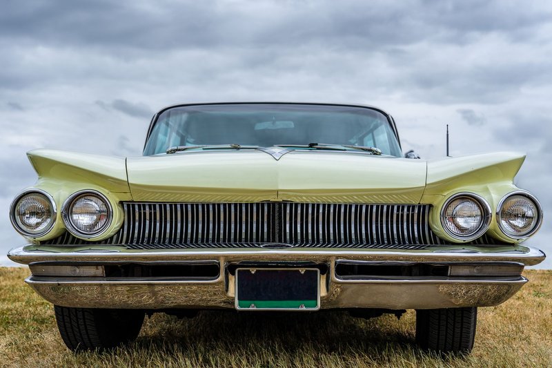 Front view of a vintage classic car with chrome detailing under a cloudy sky.