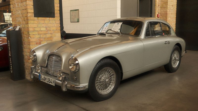 Vintage Aston Martin DB2 displayed in an indoor car showroom with a sleek silver finish.