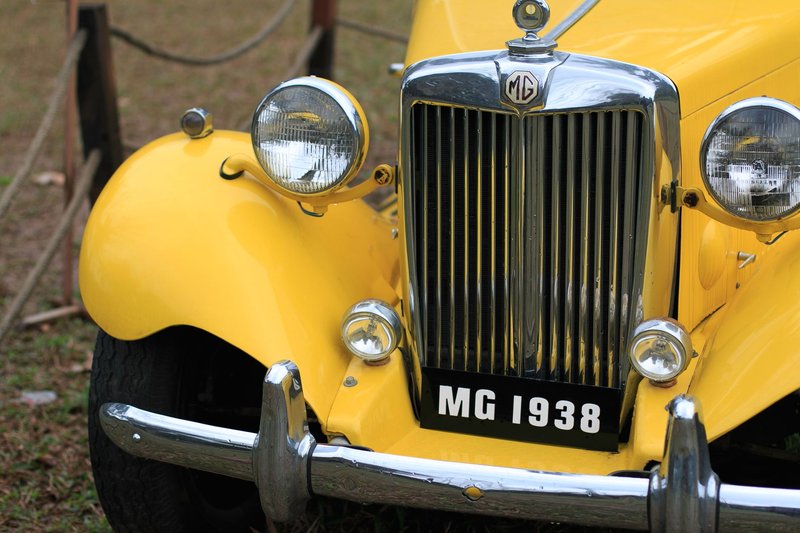 Close-up photograph of a vintage yellow MG 1938 car showcasing its front grill and headlights.
