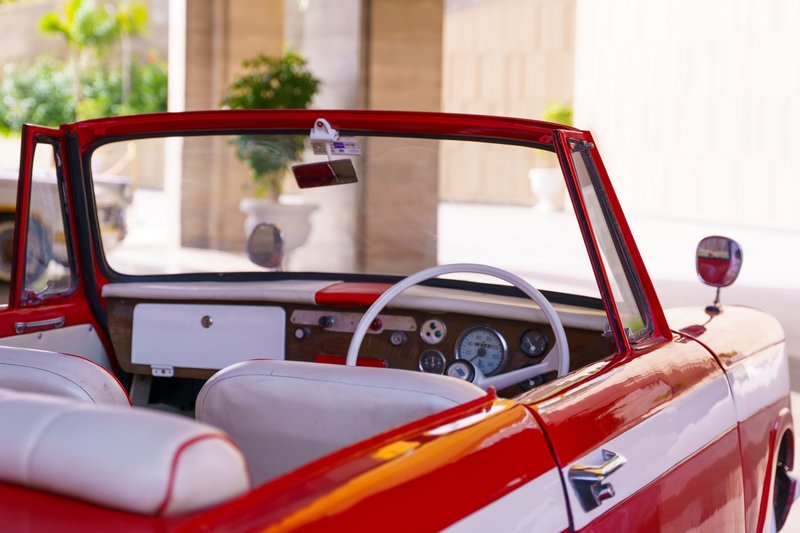 Interior of a classic red convertible car with a vintage dashboard, perfect for auto enthusiasts.