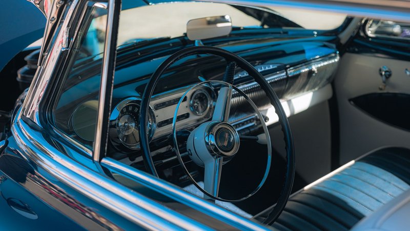 Close-up of classic Oldsmobile 88 dashboard and steering wheel, showcasing retro design elements.