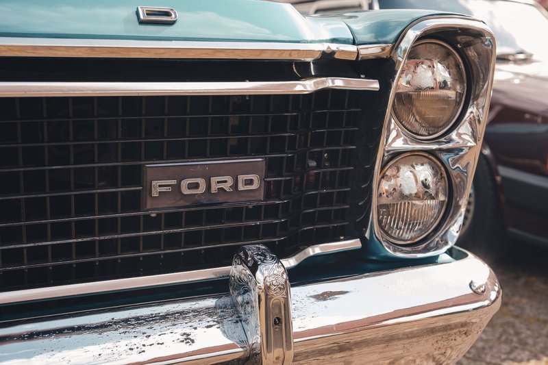 Close-up view of a vintage Ford car's grille and headlight, emphasizing its classic design.