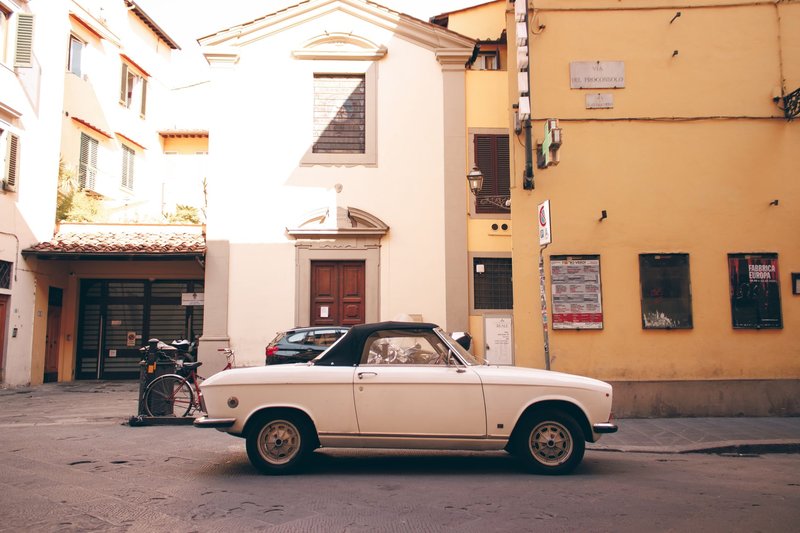 Classic white convertible car parked in historic Florence, Italy. A perfect blend of vintage charm and urban scenery.