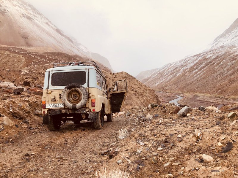 Explore rugged terrains with a vintage SUV on a remote mountain dirt road.