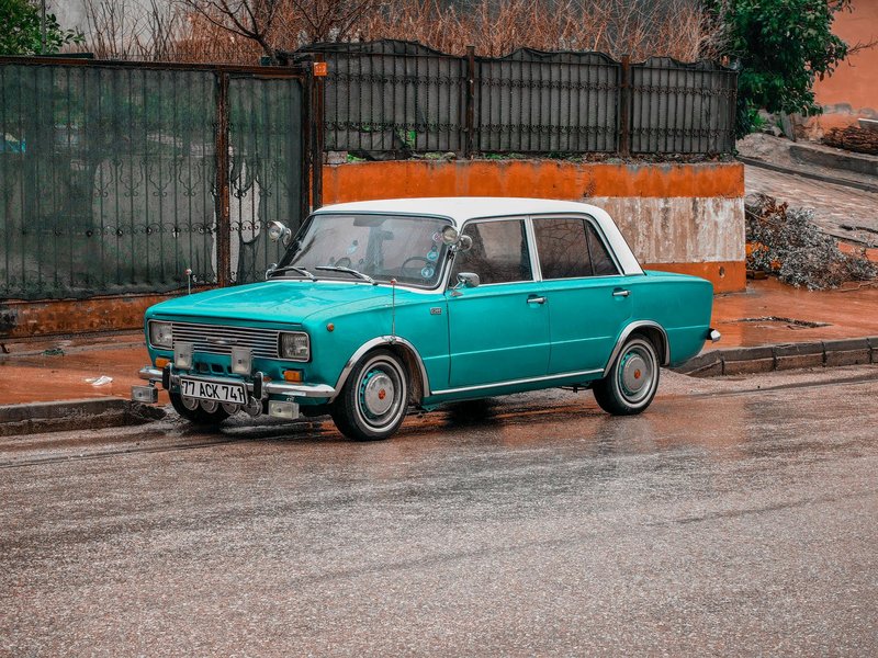 A classic turquoise sedan parked on a wet street in Yalova, Türkiye.