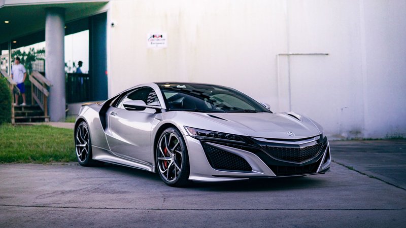 A stylish silver Acura NSX sports car parked in an urban environment, showcasing modern design and luxury.