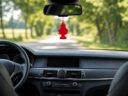 Car interior with a red tree-shaped air freshener hanging from the rear-view mirror