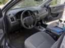 Car interior with cloth seats, unlabeled cleaning sprays, a detailing brush and microfiber towels on the passenger seat