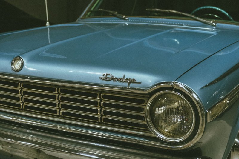 Close-up of a classic blue Dodge car's front view, highlighting its vintage design and details.