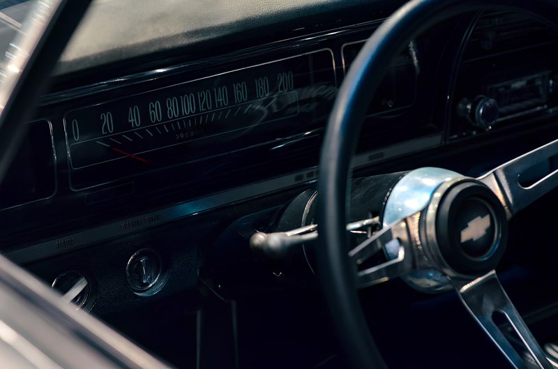 Close-up of a classic Dodge car dashboard showing the detailed speedometer and steering wheel.