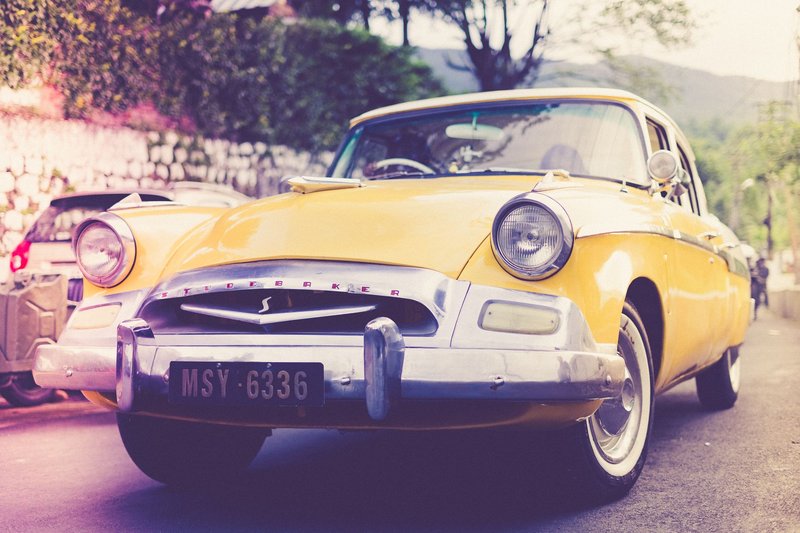 Classic yellow Studebaker car on an urban street in Shillong, India, evoking a vintage feel.
