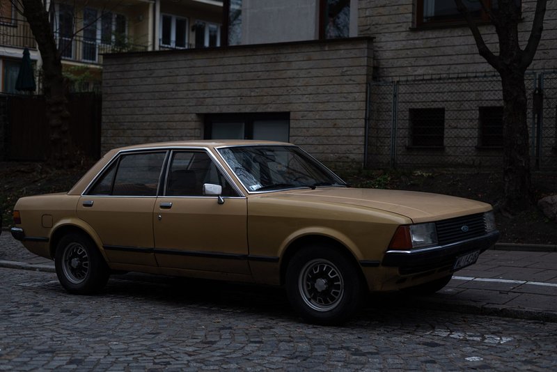 A vintage brown Ford Granada parked on city cobblestone street, evoking a classic urban atmosphere.
